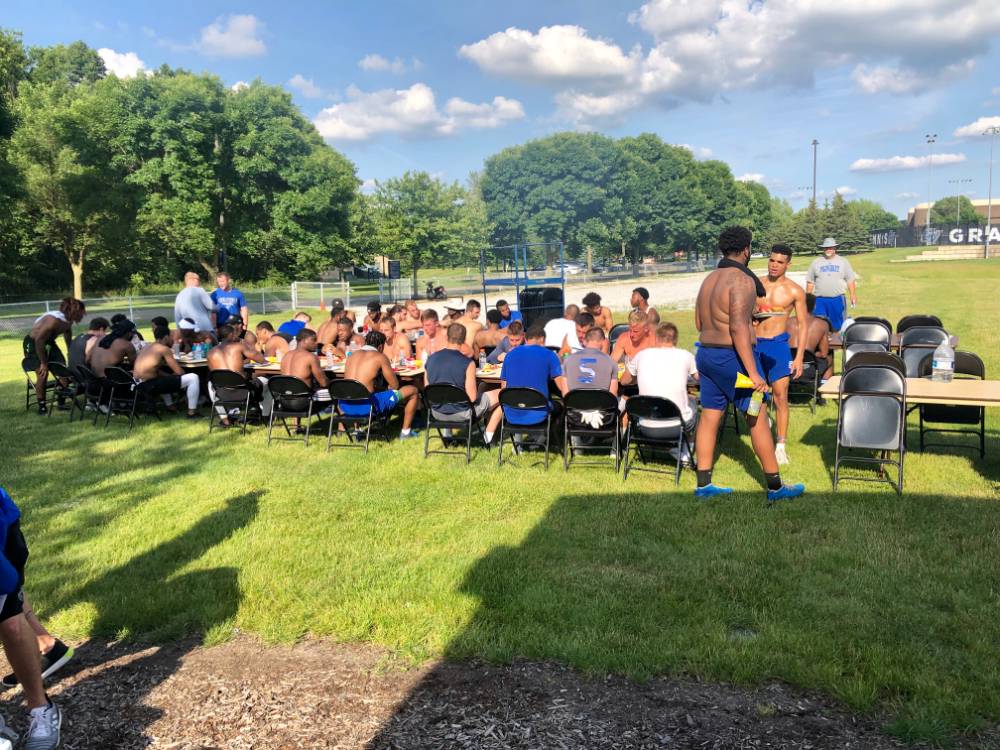 Football team eating at large table outdoors